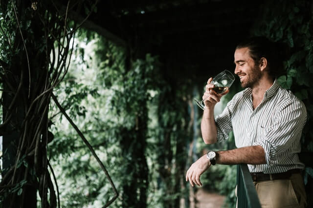 A man sniffing a glass of white wine as part of wine tasting.