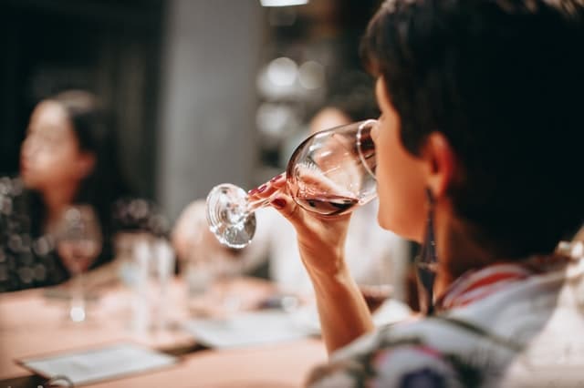 A woman sipping red wine as part of a wine tasting