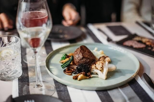 An image of a glass of wine and a steak dish