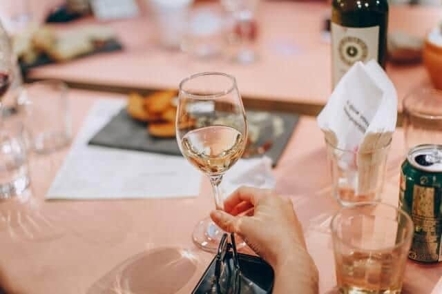 A lady holding a glass of Pinot Grigio while waiting for her meal to be served.