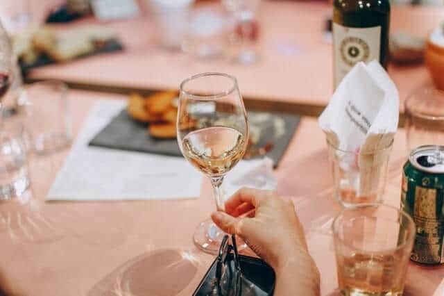 A lady holding a glass of Pinot Grigio while waiting for her meal to be served.