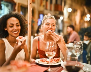 An image of two girls enjoying their pizza and wine pairing
